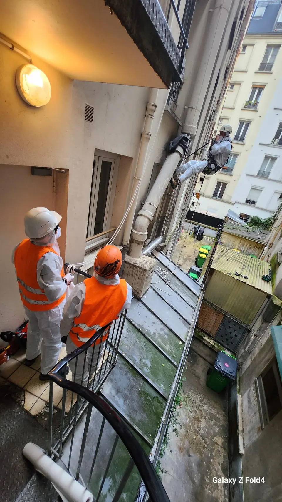 Dépose d'un conduit en fibro-ciment amianté en cour intérieure à Paris par une équipe de cordistes en protection respiratoire